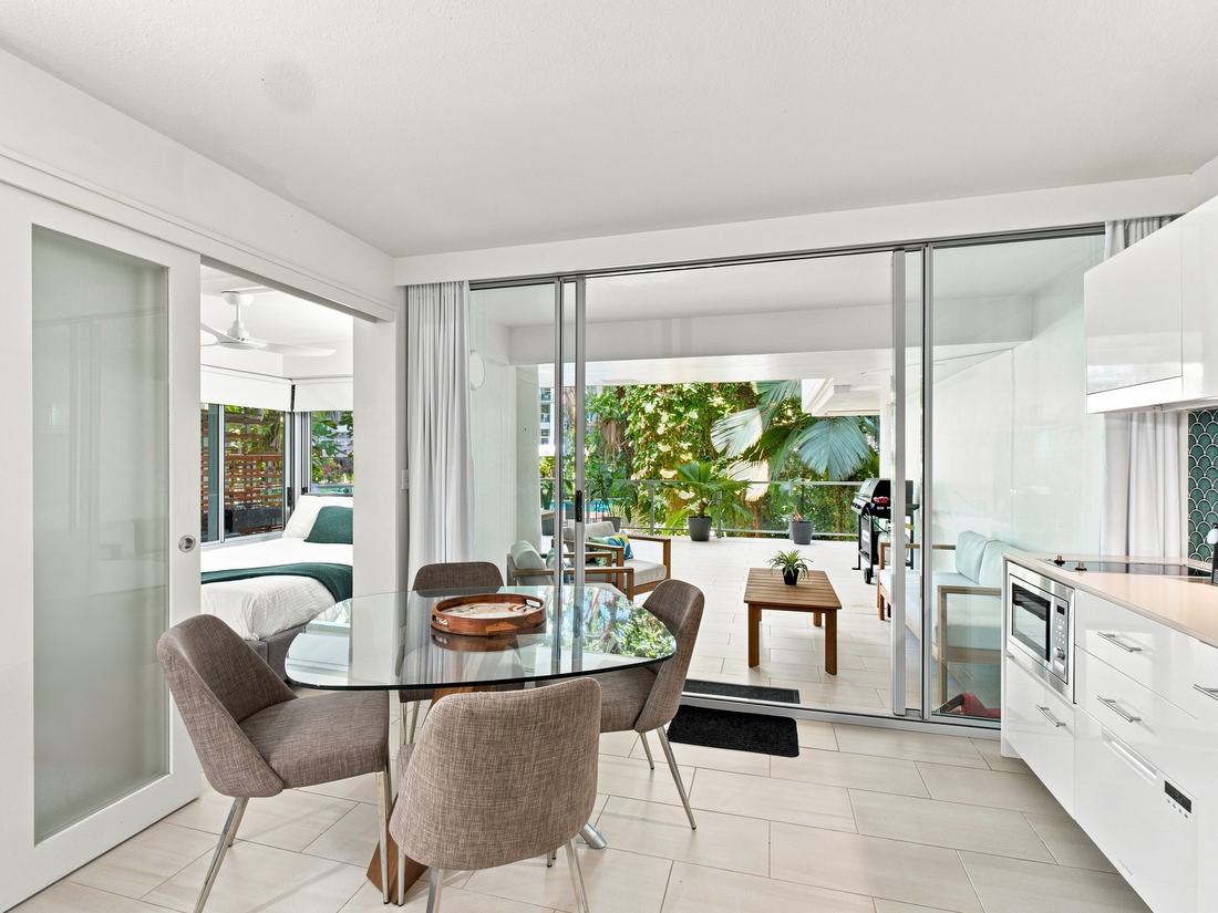 Dining area opening through glass sliders to a tropical balcony