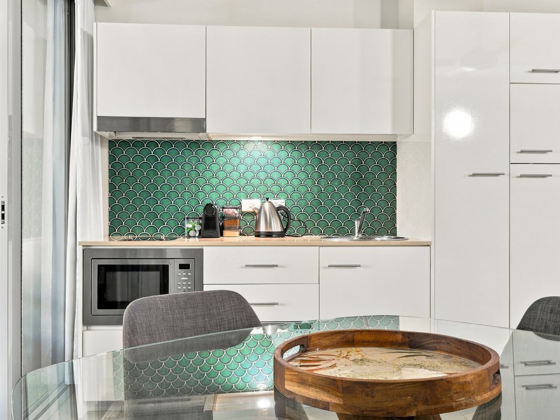 White kitchen with a green fish-scale tile splashback