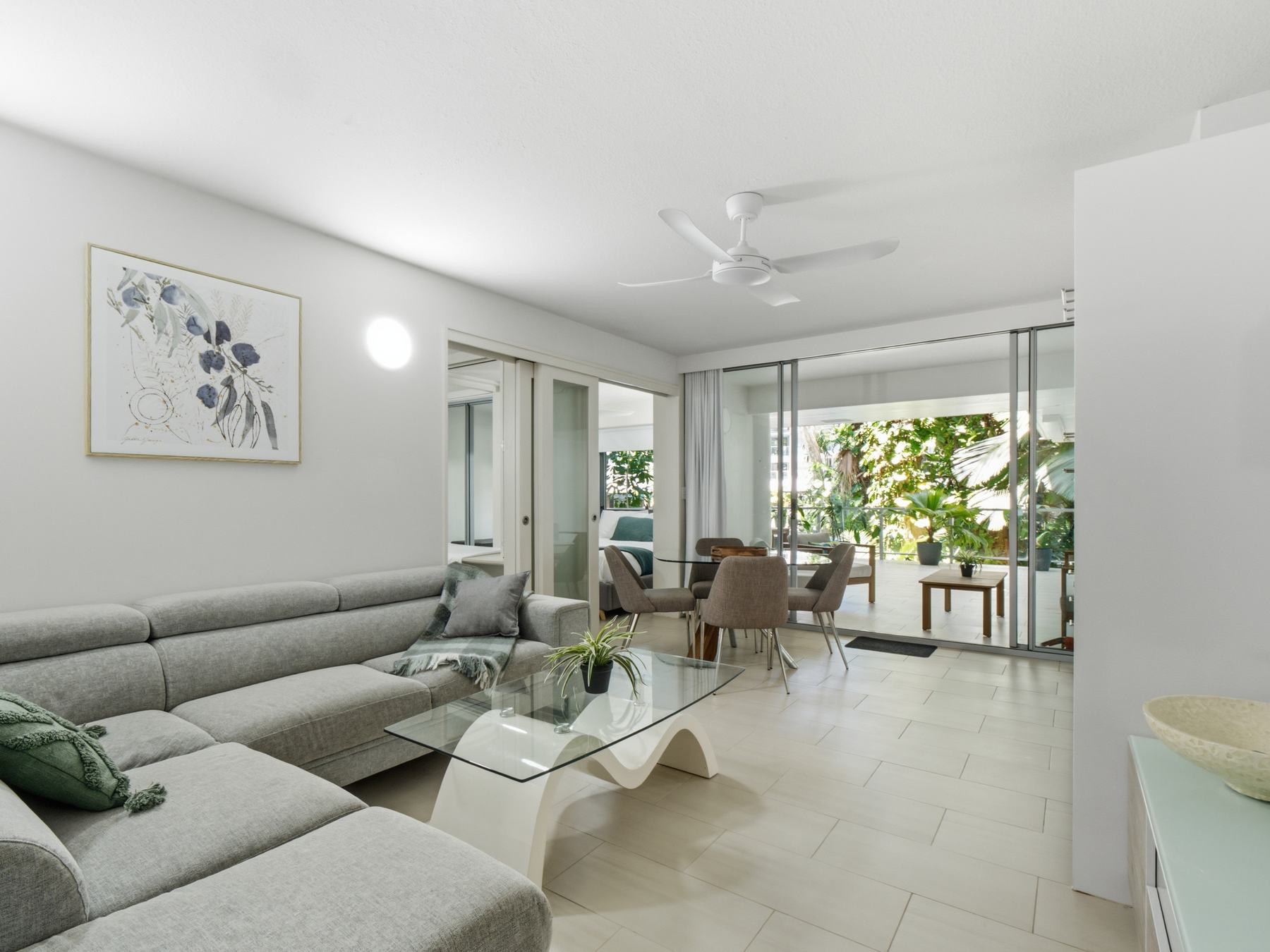 Bright open-plan living room flowing out to a rainforest balcony